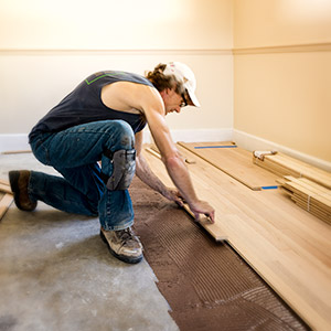 A man installing hardwood flooring over a concrete subfloor